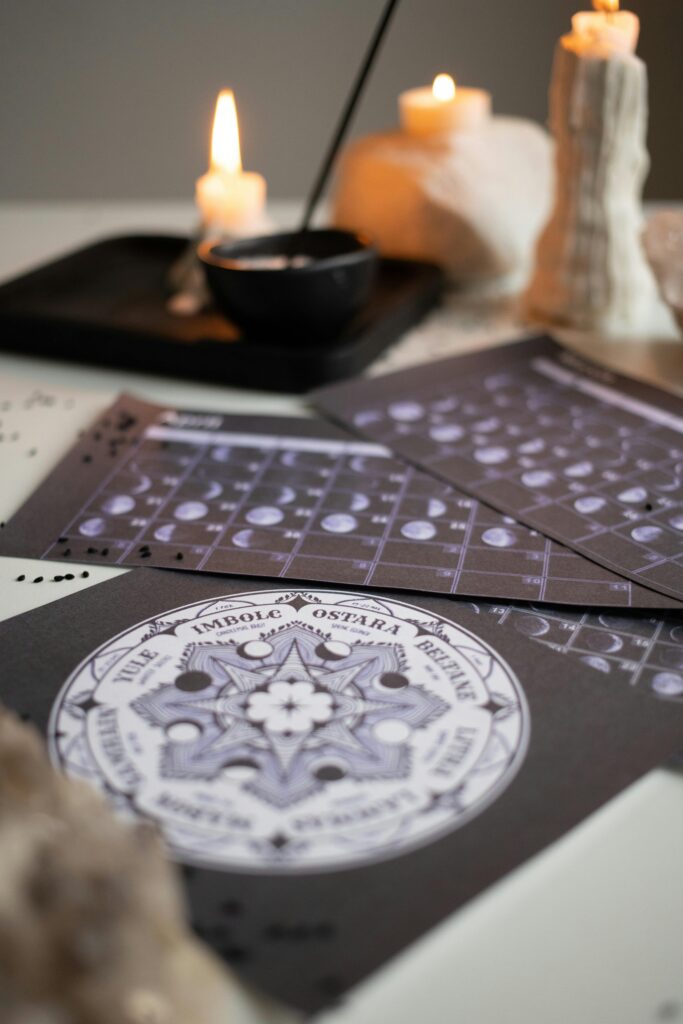 A mystical setup with candles, moon phase calendars, and spiritual symbols on a table.