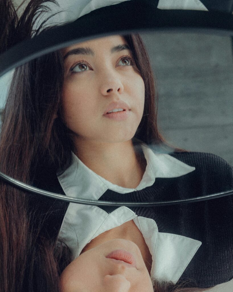 Artistic portrait of a woman with a reflective mirror, focused expression
